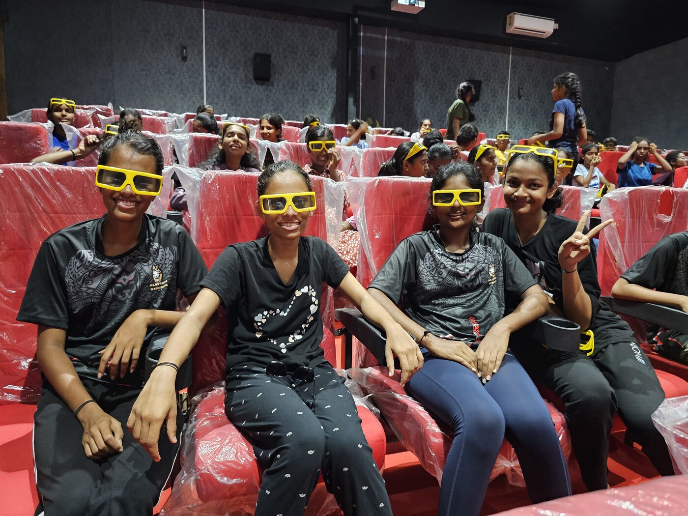 Students in 3D glasses inside the theatre, laughing